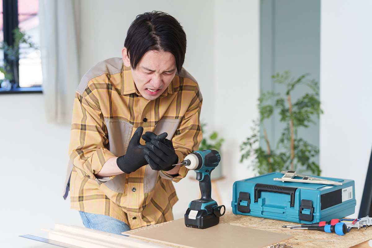 電動ドリルで指に怪我をする男性