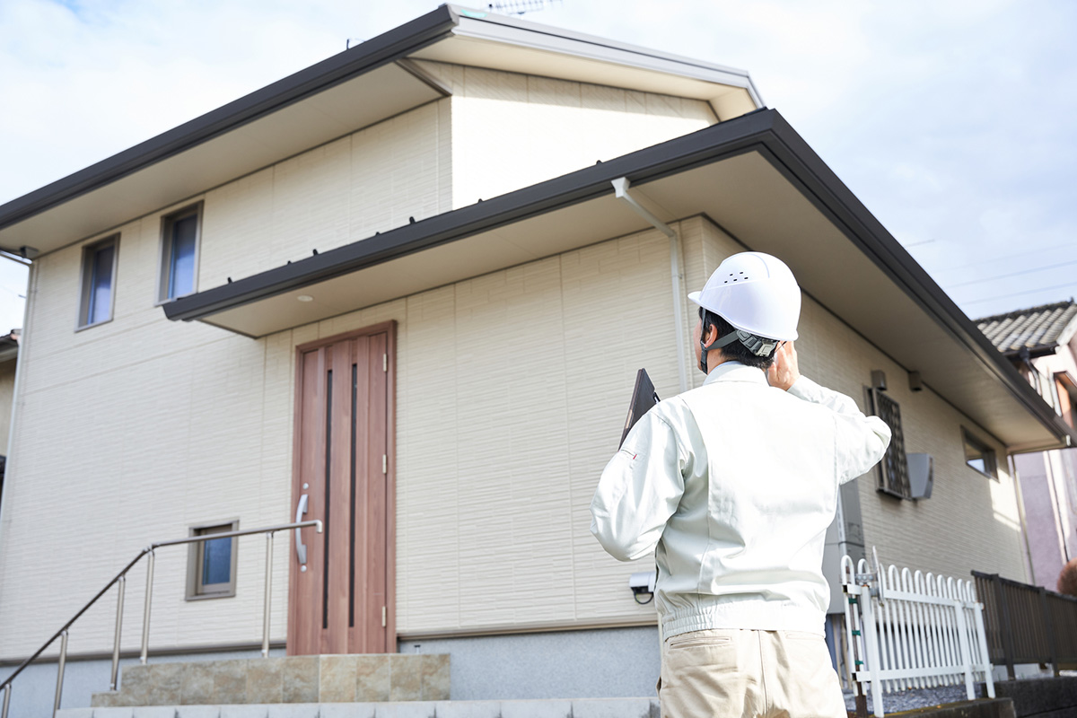 戸建ての前に立つ作業員